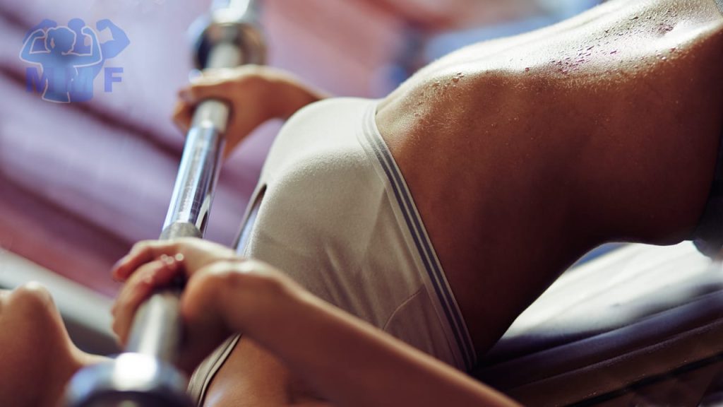 Woman performing barbell push crunch on decline bench