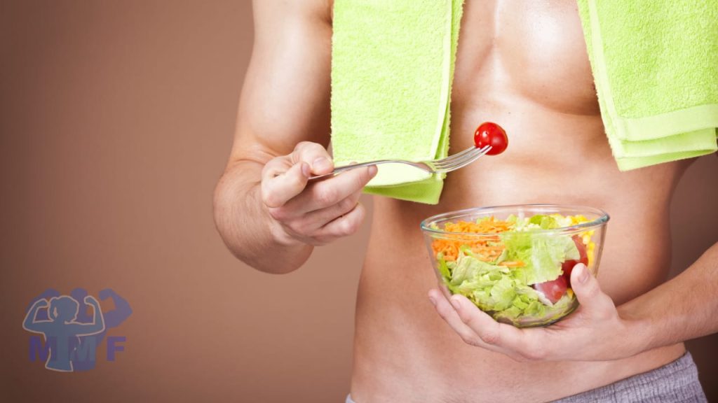 Strong fit shirtless man eating a salad with a green towel around his neck, with a cherry tomato on his fork wonder is calorie restriction and longevity true.