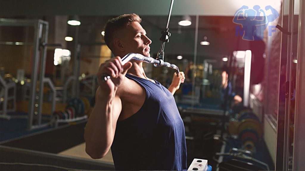 Fit man performing lat pulldowns in a gym.